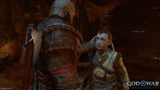 Video game screenshot of God of War protagonist Kratos with his back to the camera, facing his teenage son
